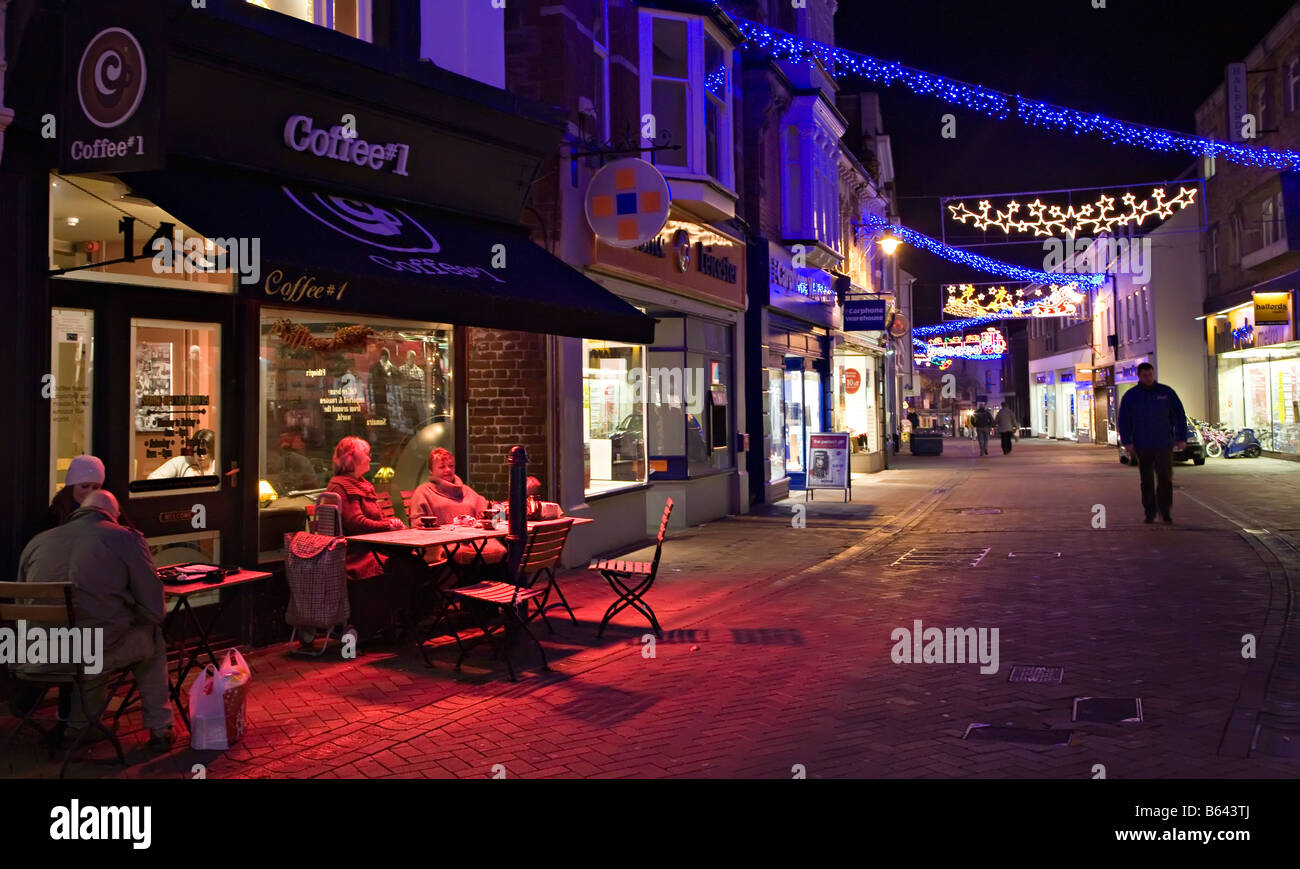 Le persone al tavolo del bar in strada pedonale al tramonto con le luci di Natale ad Abergavenny Wales UK Foto Stock