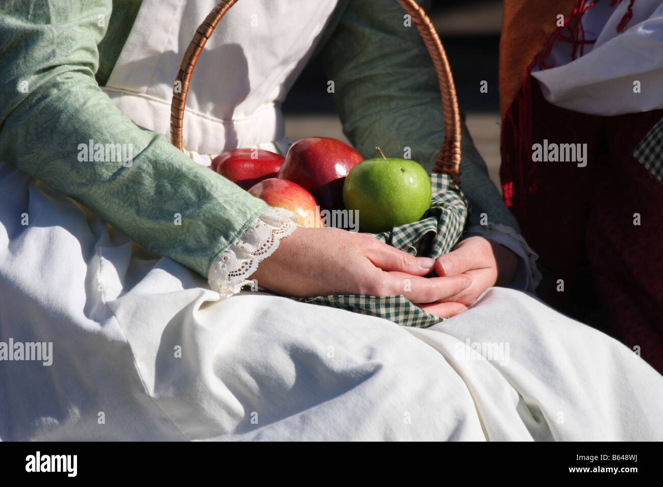 Una giovane donna in una prateria western dress seduta con una ciotola di mele nel suo giro Foto Stock