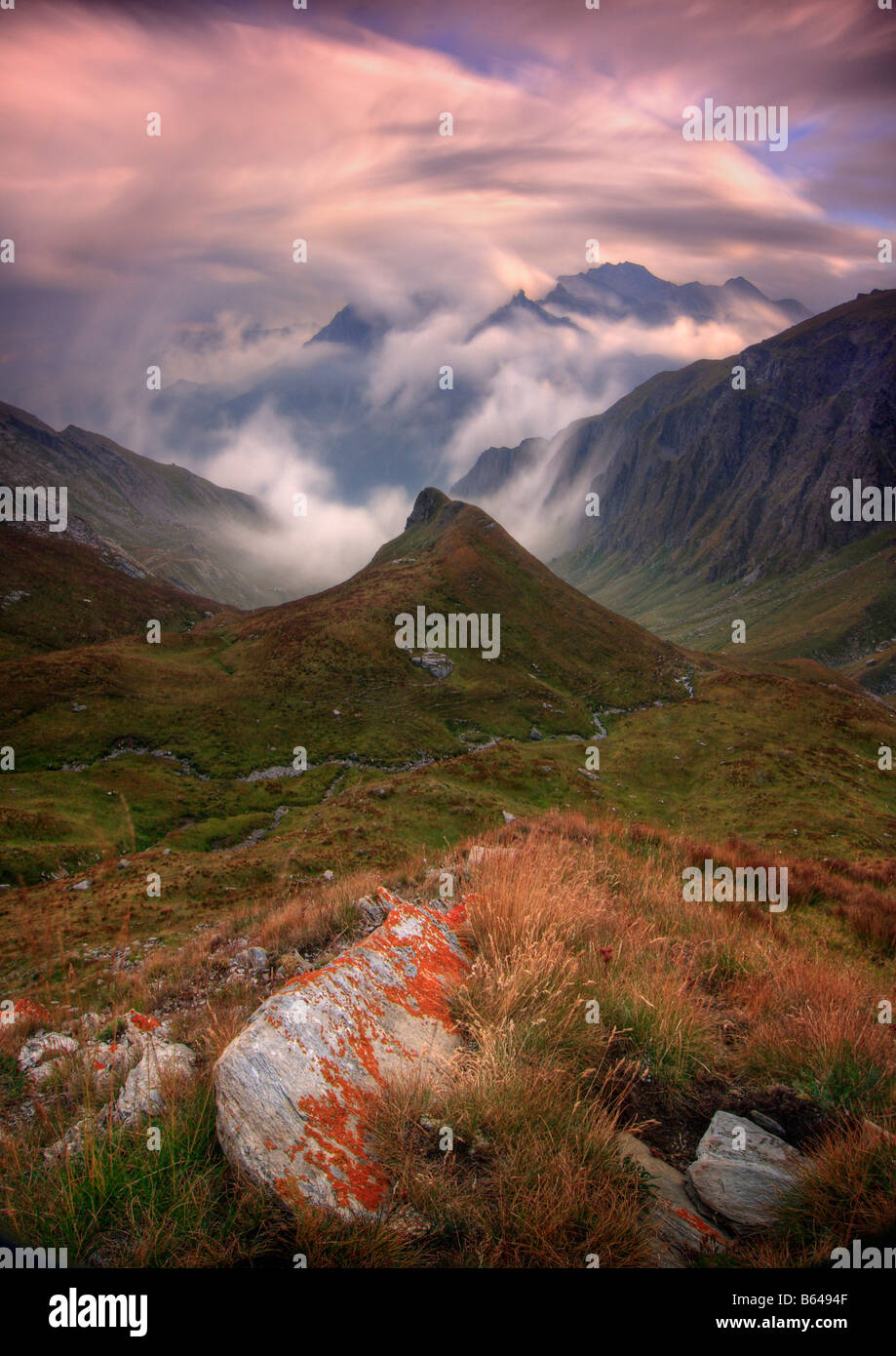 Il rotolamento banchi di nebbia e in rapido movimento di cloud davanti al tramonto italiani nelle Alpi occidentali Foto Stock