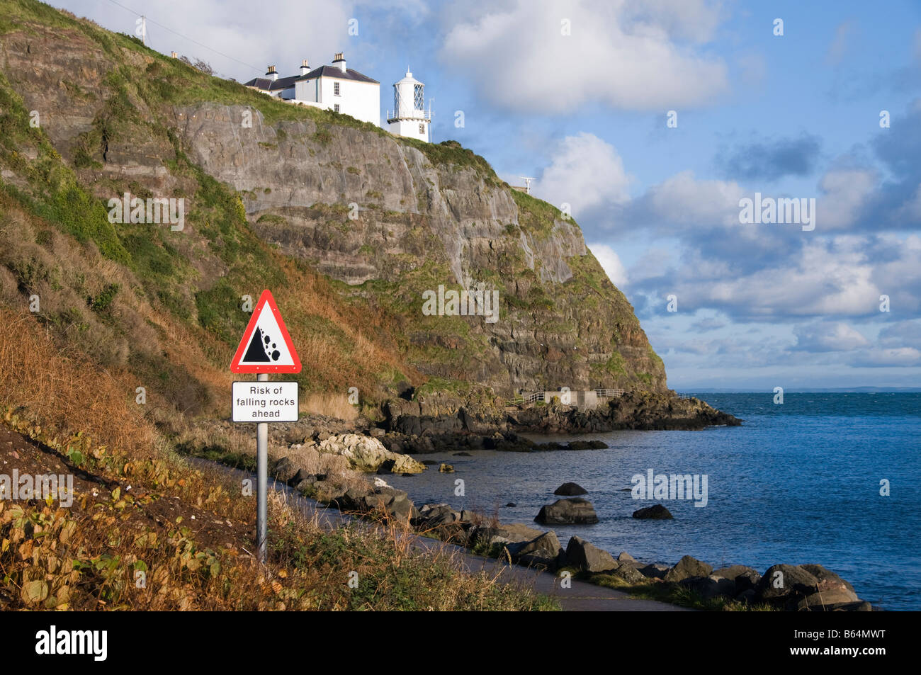 Whitehead/Blackhead Faro sulla scogliera sopra Belfast Lough. Pericolo caduta massi segno. Foto Stock