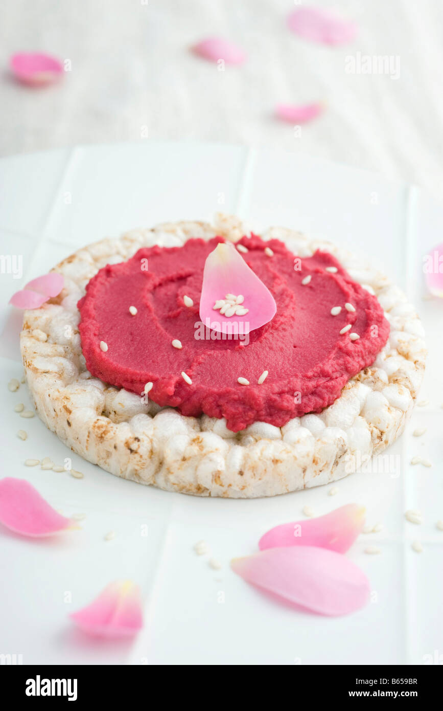 La purea di barbabietole e petali di fiori sul cracker di riso Foto Stock