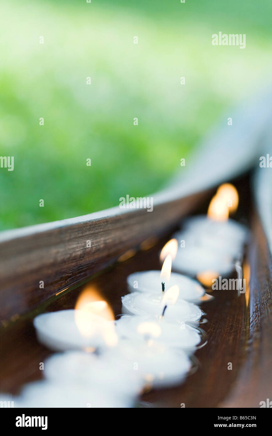 Acceso candele votive galleggianti in acqua entro a tazza di foglie di palma Foto Stock