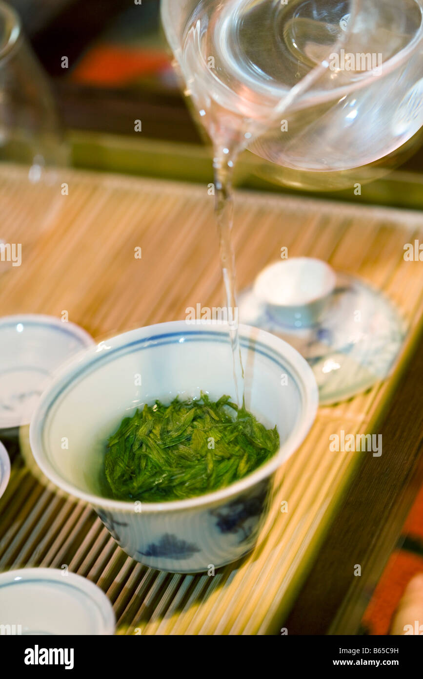 Acqua calda versata dalla teiera di vetro sopra le foglie di tè in gaiwan cup Foto Stock