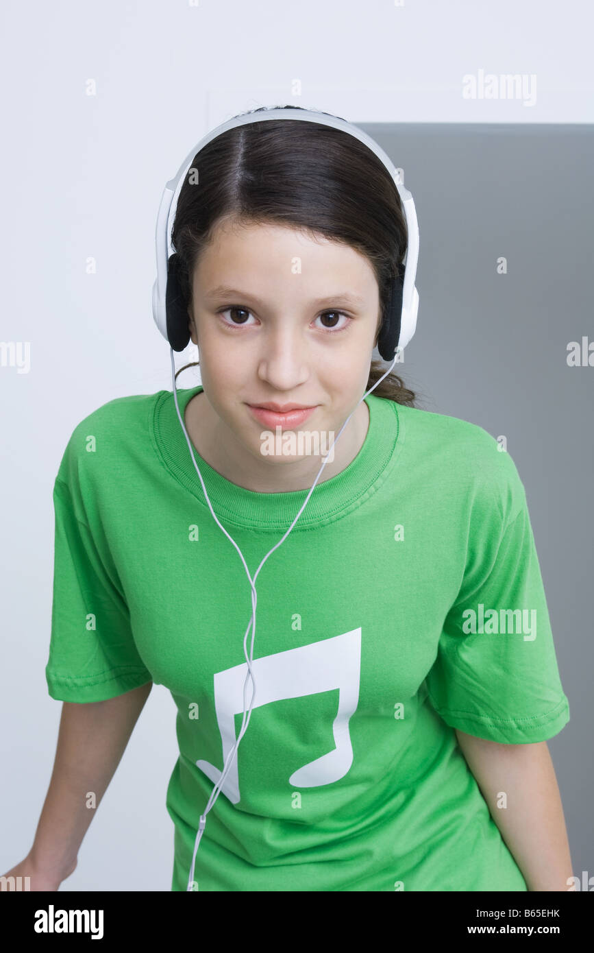 Ragazza Preteen indossando tee-shirt stampata con note musicali, ascoltare le cuffie, sorridente Foto Stock