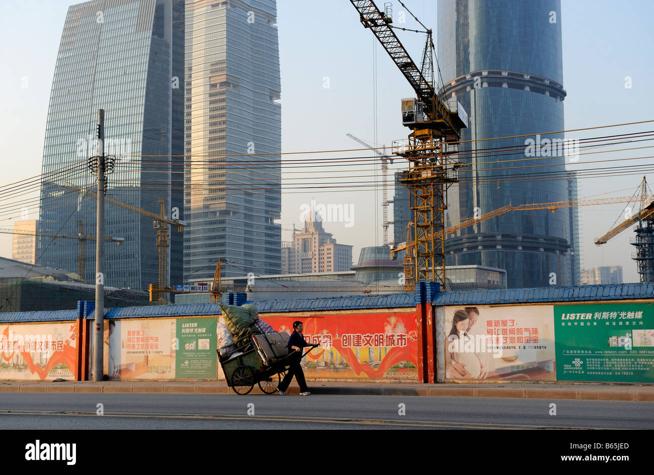 Una donna che trasporta i sacchi e i rifiuti di carta su un camion sul marciapiede davanti a un cantiere in Guangzhou. 26-Nov-2008 Foto Stock