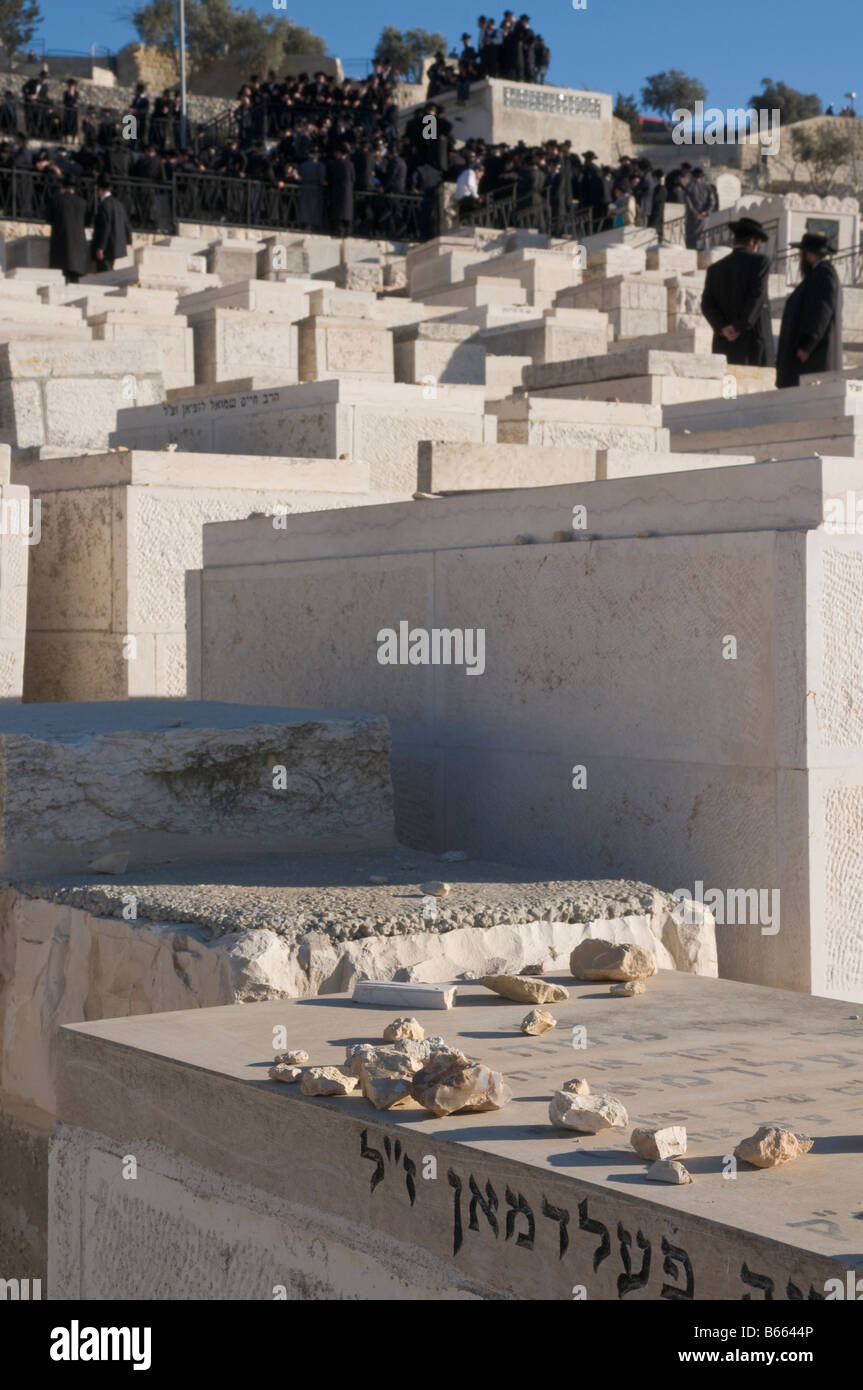 Israele Gerusalemme Monte degli Ulivi cimitero ebraico close up di pietre sulle tombe con un gruppo di ebrei ortodossi in bkgd Foto Stock