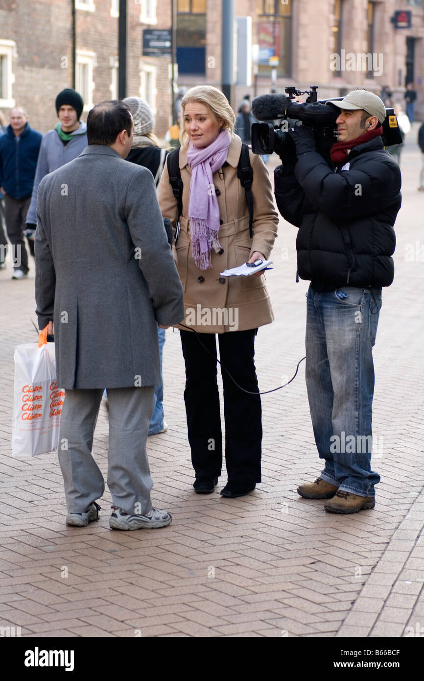 Una troupe cinematografica interviste un membro del pubblico in strada. Foto Stock