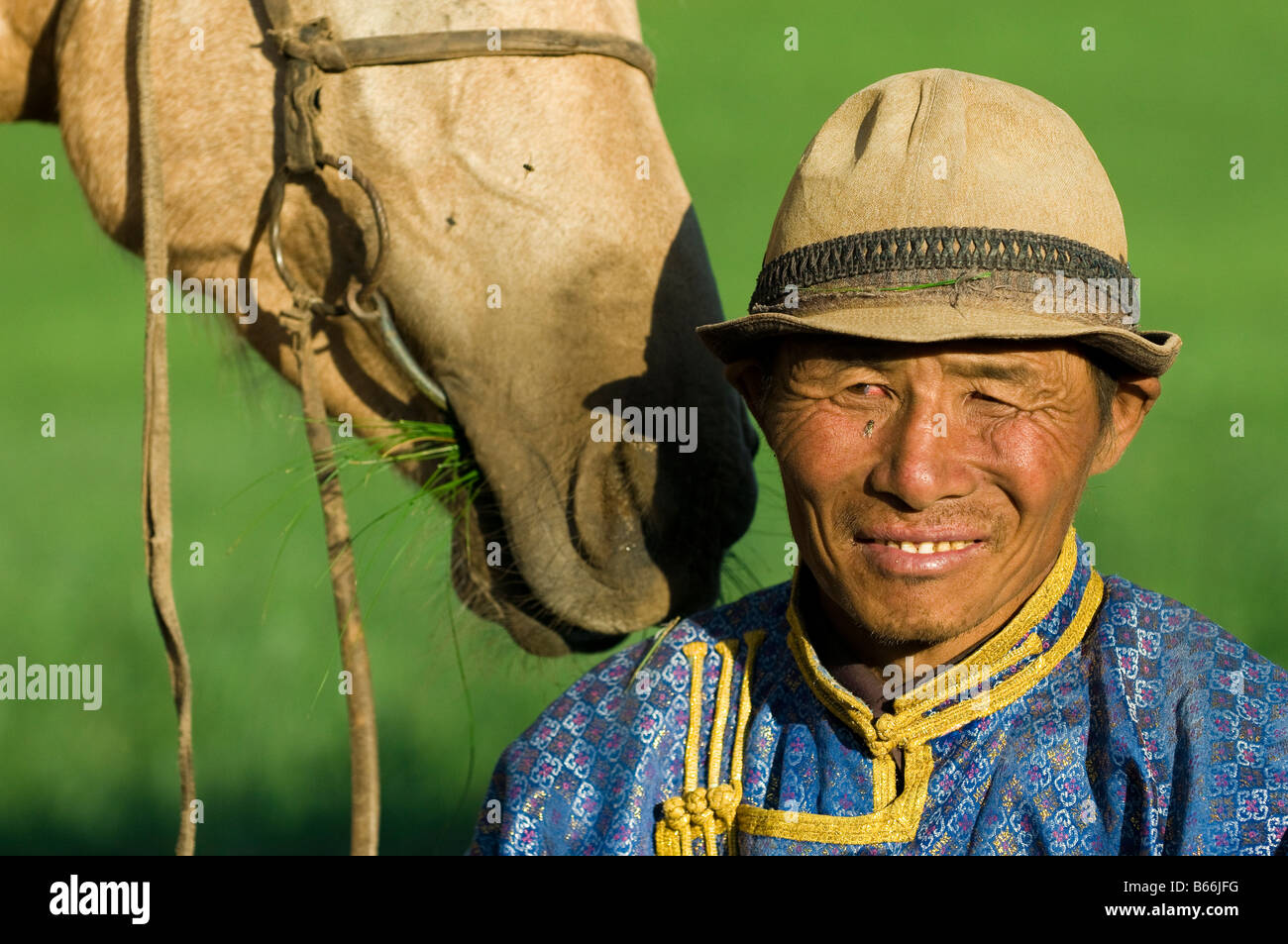 Praterie pastore in abito tradizionale con erba mangiare cavallo Xilinhot Inner Mongolia Cina Foto Stock