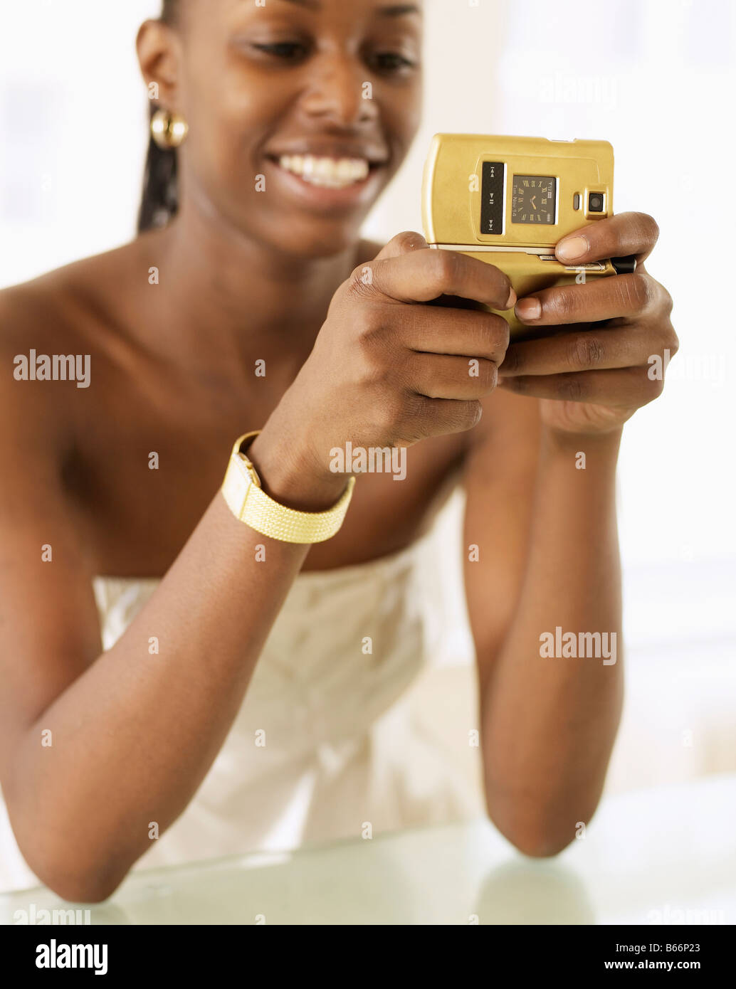 Giovane donna alla messaggistica di testo con telefono dorato Foto Stock