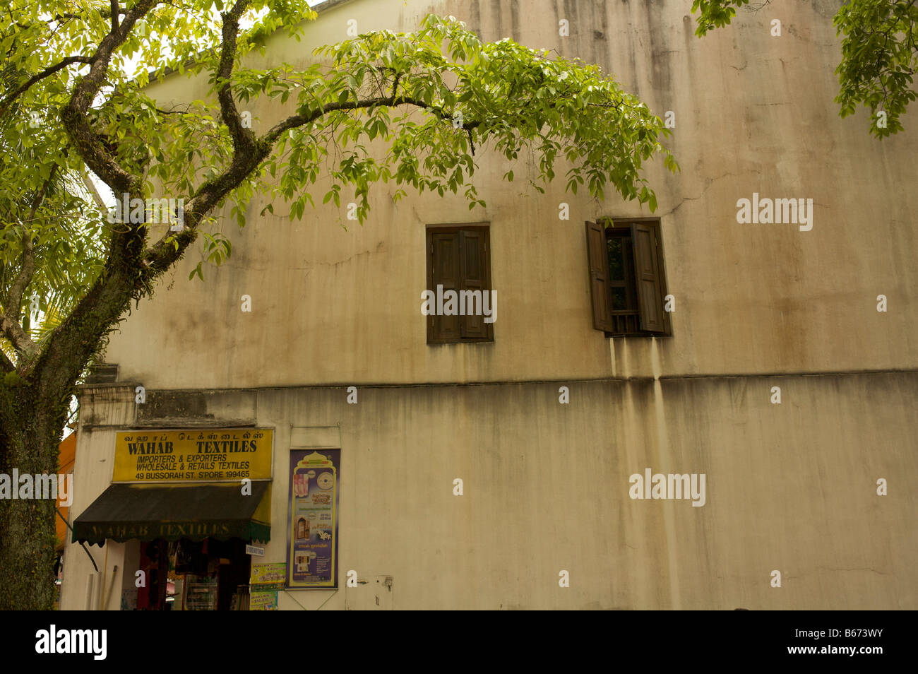 Finestre con persiane al primo piano del vecchio edificio rustico di Singapore Foto Stock