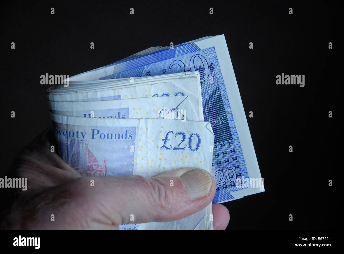 Manciata di inglese £20 notes detenute in un rotolo Foto Stock
