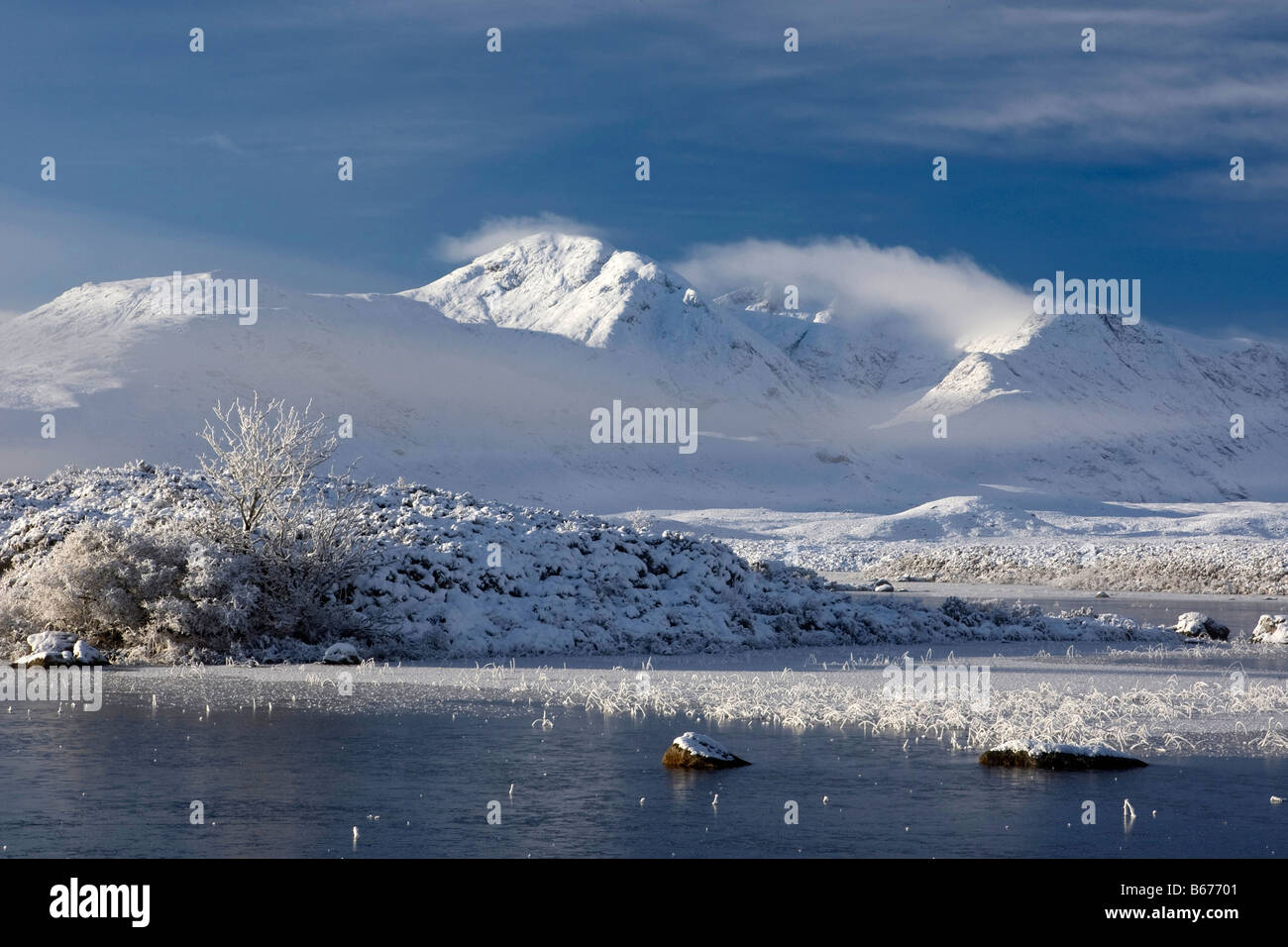 Bel mattino scena attraverso Rannoch Moor evidenziando la mattina presto mist, congelata di loch, e neve mozzafiato sulle montagne Foto Stock