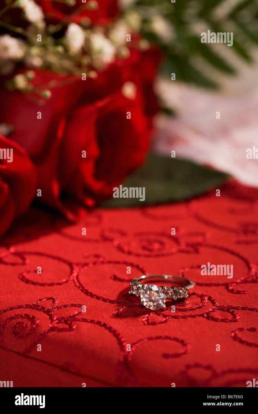 Anello di fidanzamento sulla casella rossa e le rose Foto Stock