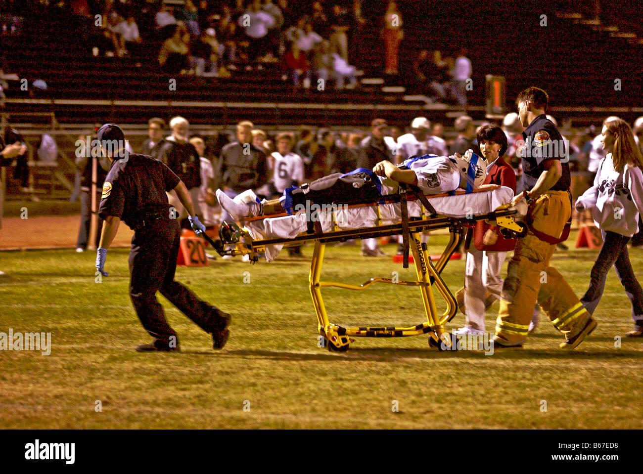 Feriti di alta scuola calcio giocatore è gommato da campo da personale paramedico durante una notte di gioco in California del Sud Foto Stock