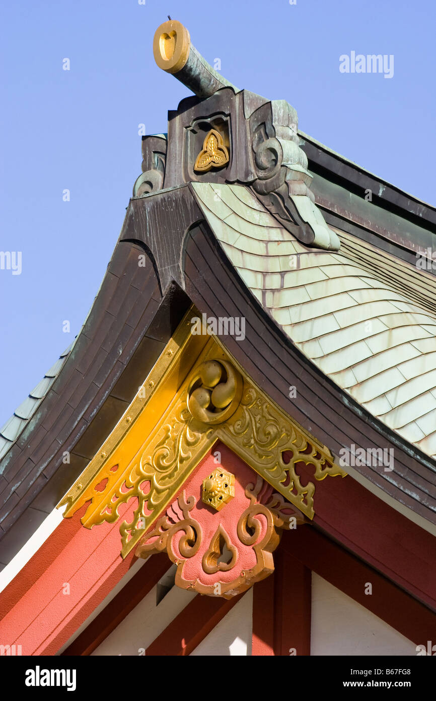 Dettaglio del tetto di un santuario giapponese shintoista che mostra l'Onigawara, (piastrella di cresta), e Kegyo, (disegno decorativo) tegola triangolare con sfondo blu del cielo. Foto Stock