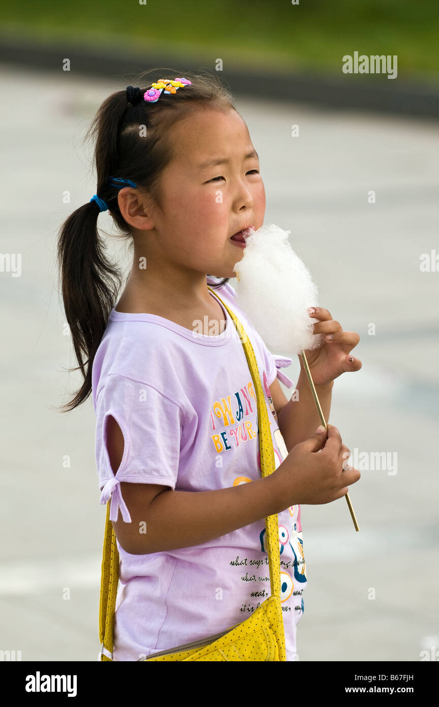 Ragazza giovane mangia la caramella di cotone in town square Xiwuzhumuqinqi Inner Mongolia Cina Foto Stock