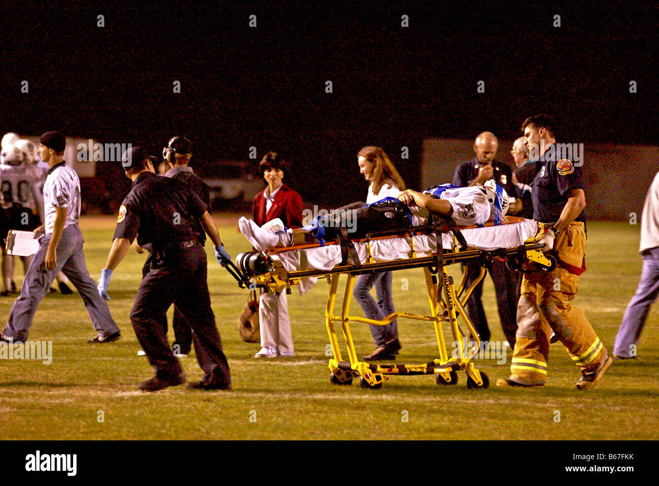 Feriti di alta scuola calcio giocatore è gommato da campo da personale paramedico durante una notte di gioco in California del Sud Foto Stock