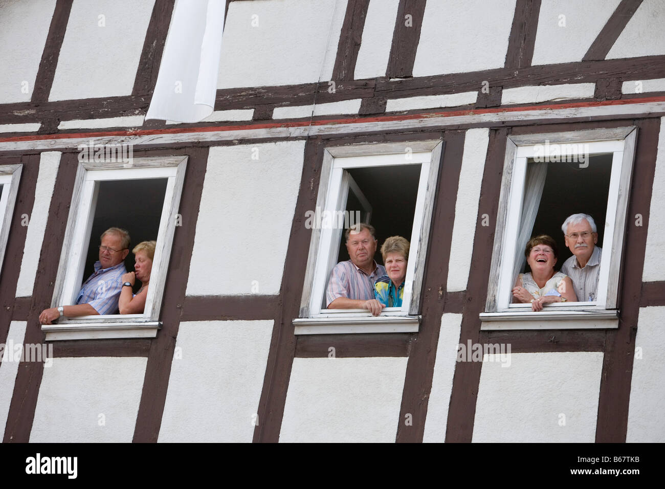 Spettatori guardando fuori attraverso le finestre di una casa timberframe, Schlitz Festival Internazionale, Schlitzerlaender Trachten und egli Foto Stock