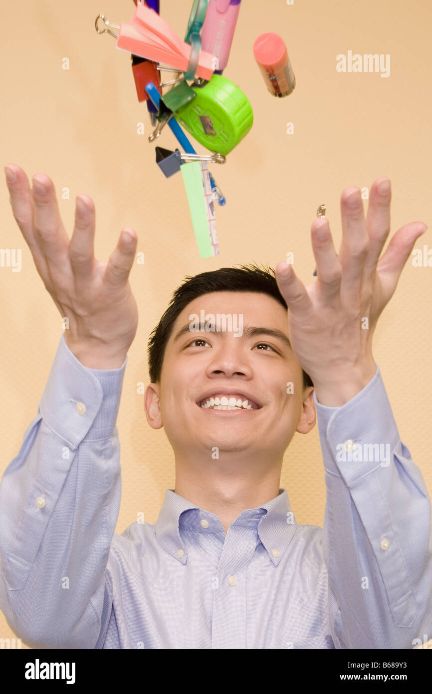 Close-up di un giovane uomo di lanciare oggetti di cancelleria e sorridente Foto Stock