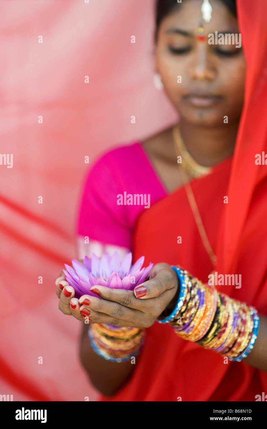 Donna indiana offre un Nymphaea ninfea tropicale fiore in un sari rosso. Andhra Pradesh, India Foto Stock