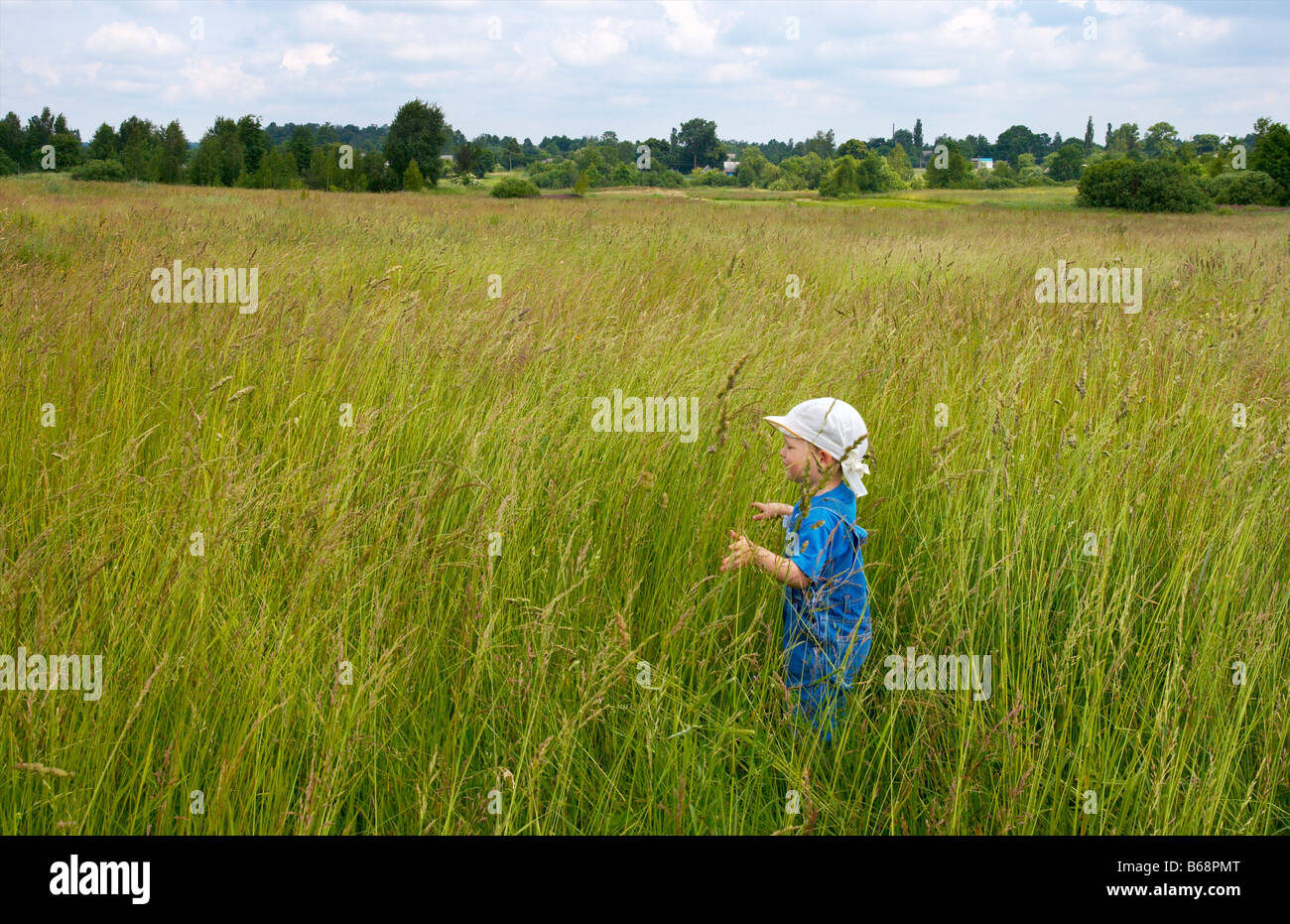 Il pianto piccolo ragazzo in tallgrass sul prato estivo Foto Stock