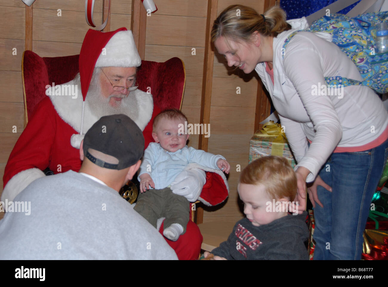 Una famiglia si riunisce intorno a Santa clausola durante una visita con i bambini. Foto Stock