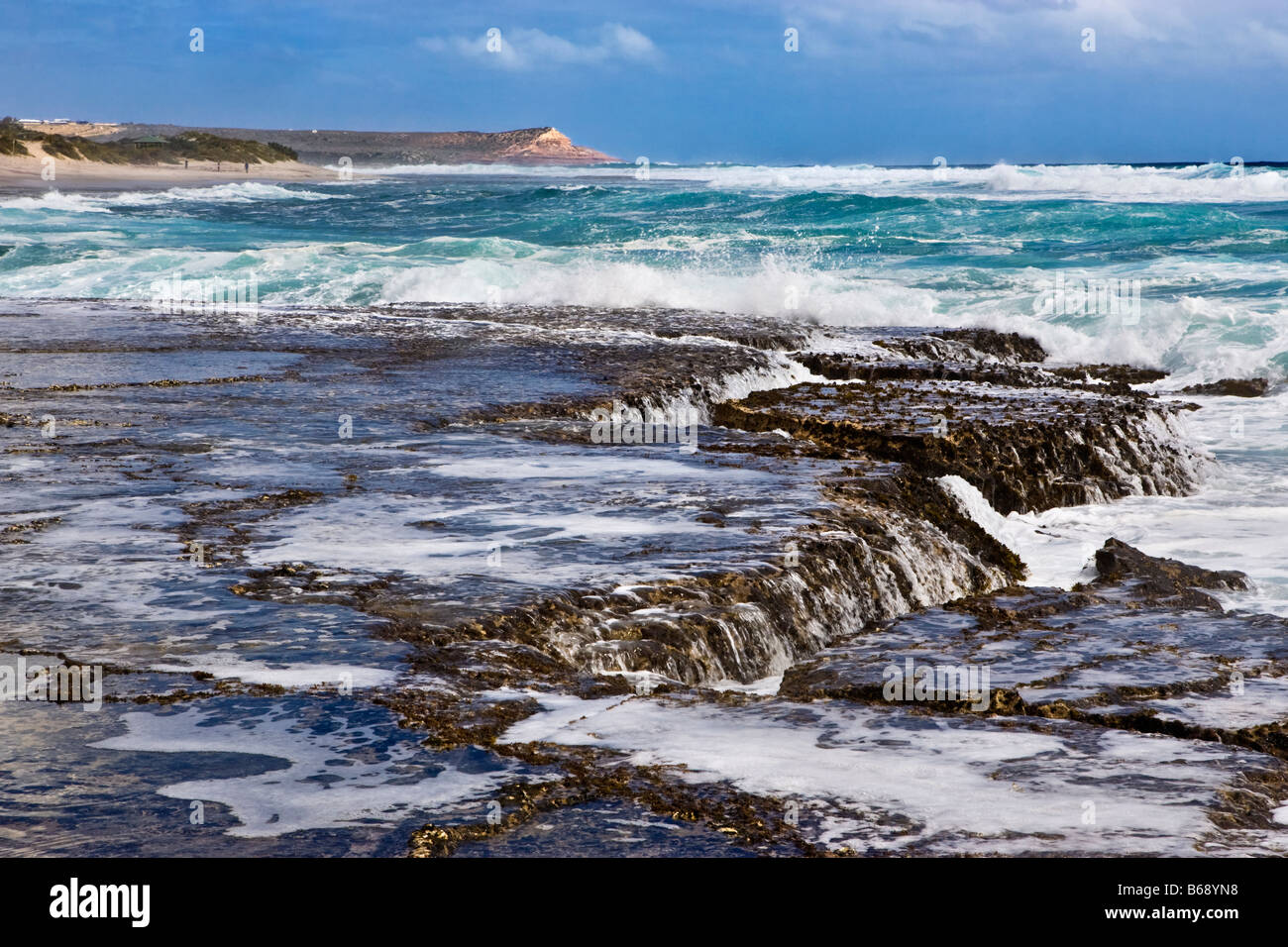 Onde che si infrangono sulla costa rocciosa di Kalbarri National Park con Red Bluff nella distanza, Australia occidentale Foto Stock