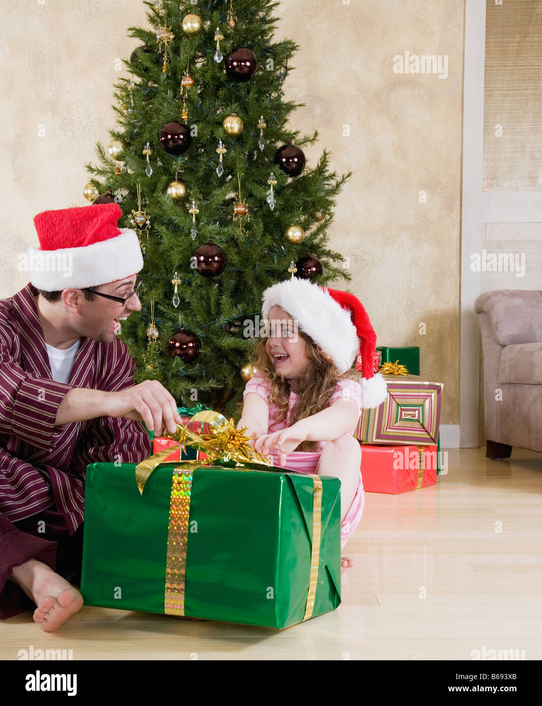 Padre e figlia (5-6) in cappelli di Babbo Natale Natale apertura presente Foto Stock