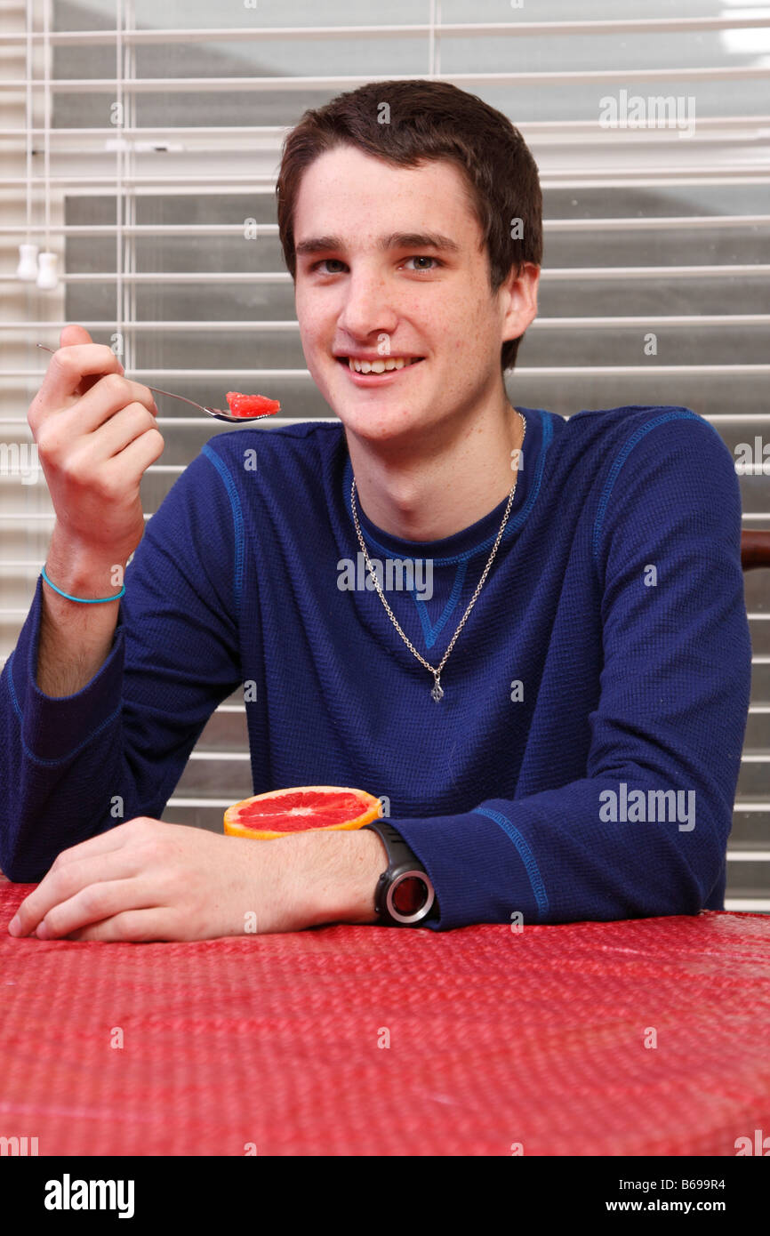 Teen mangiando un pompelmo per la prima colazione Foto Stock