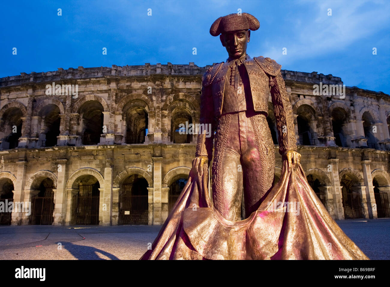 Statua del torero di fronte all'Arena nella città francese di Nimes all'imbrunire, sud della Francia, Europa Foto Stock