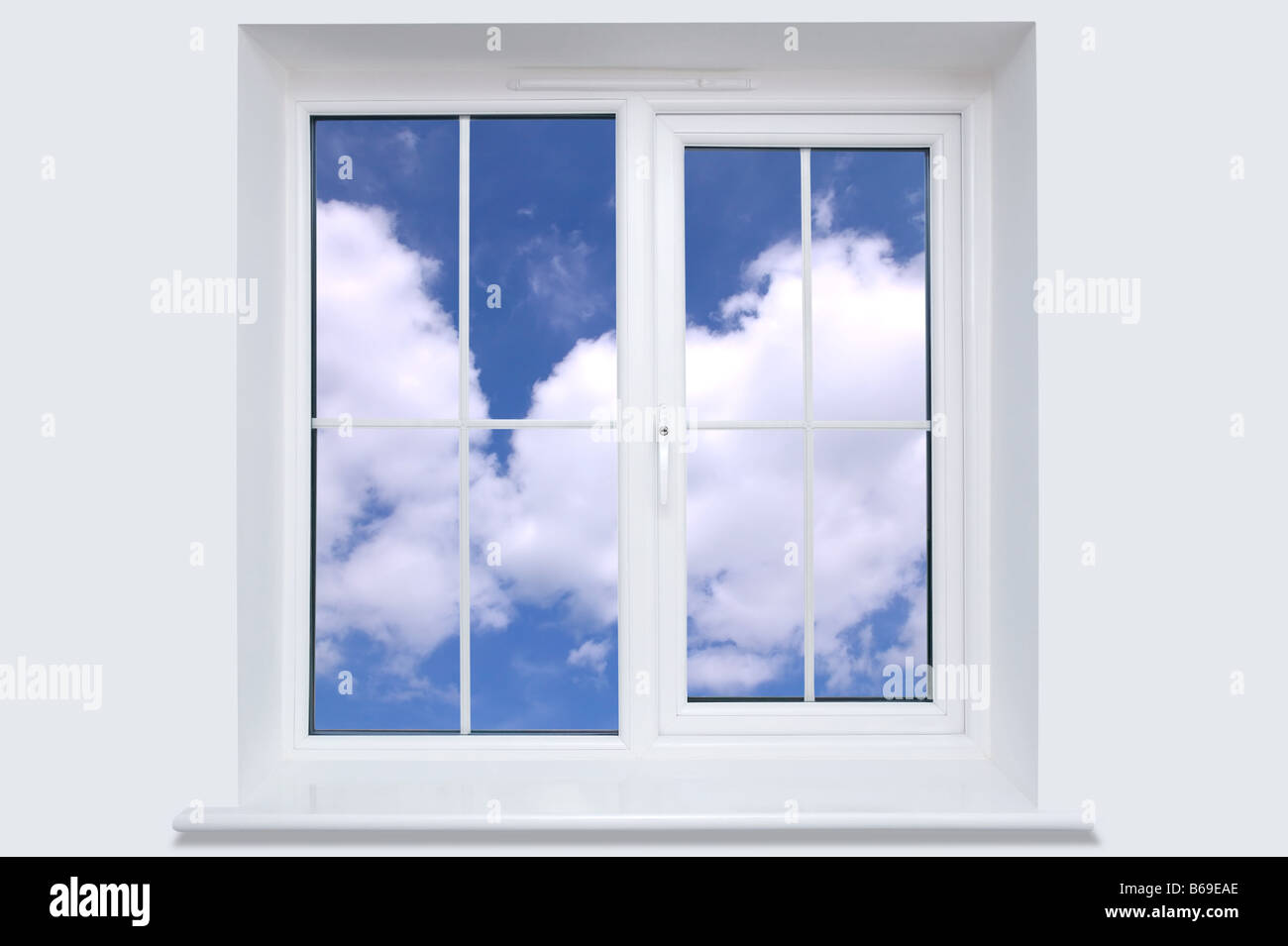 Blu cielo nuvoloso sembrano attraverso una finestra bianca telaio Foto Stock