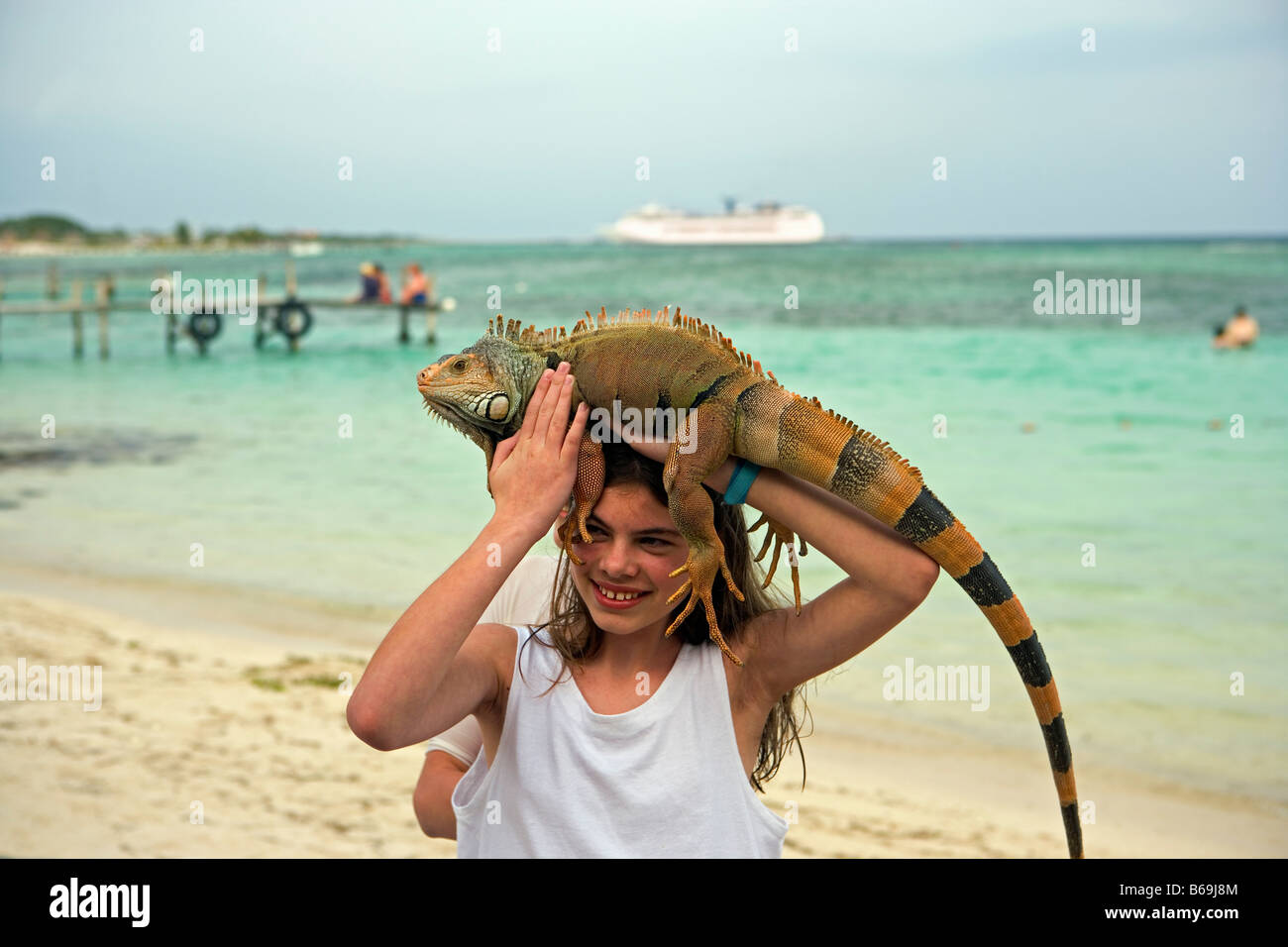 Messico. Majahuala. Quintana Roo, donna sulla spiaggia con iguana con la nave di crociera in background. Foto Stock