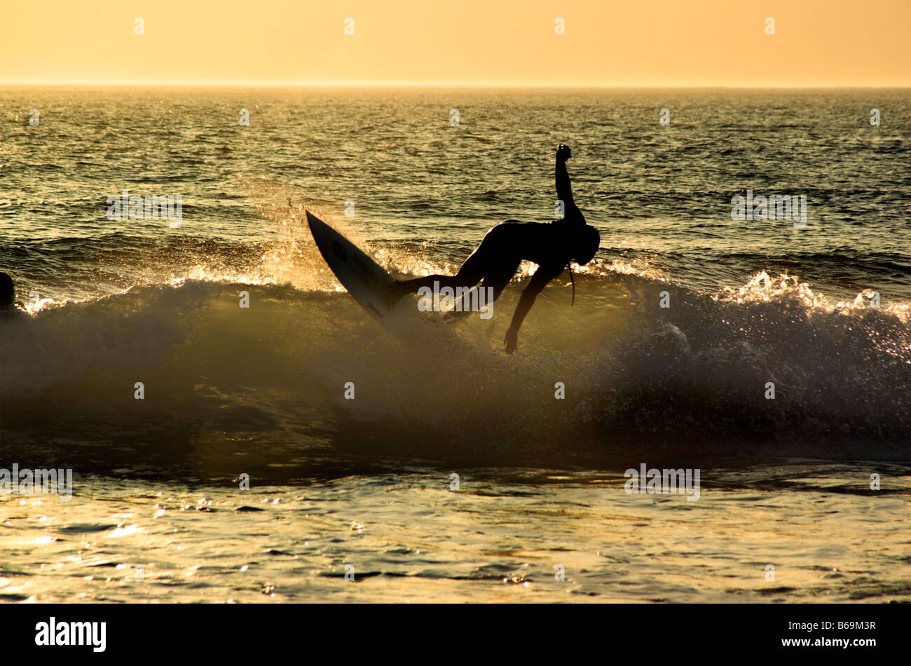 Un surfista in azione su un onda al tramonto a Woolacombe Beach in Devon Foto Stock