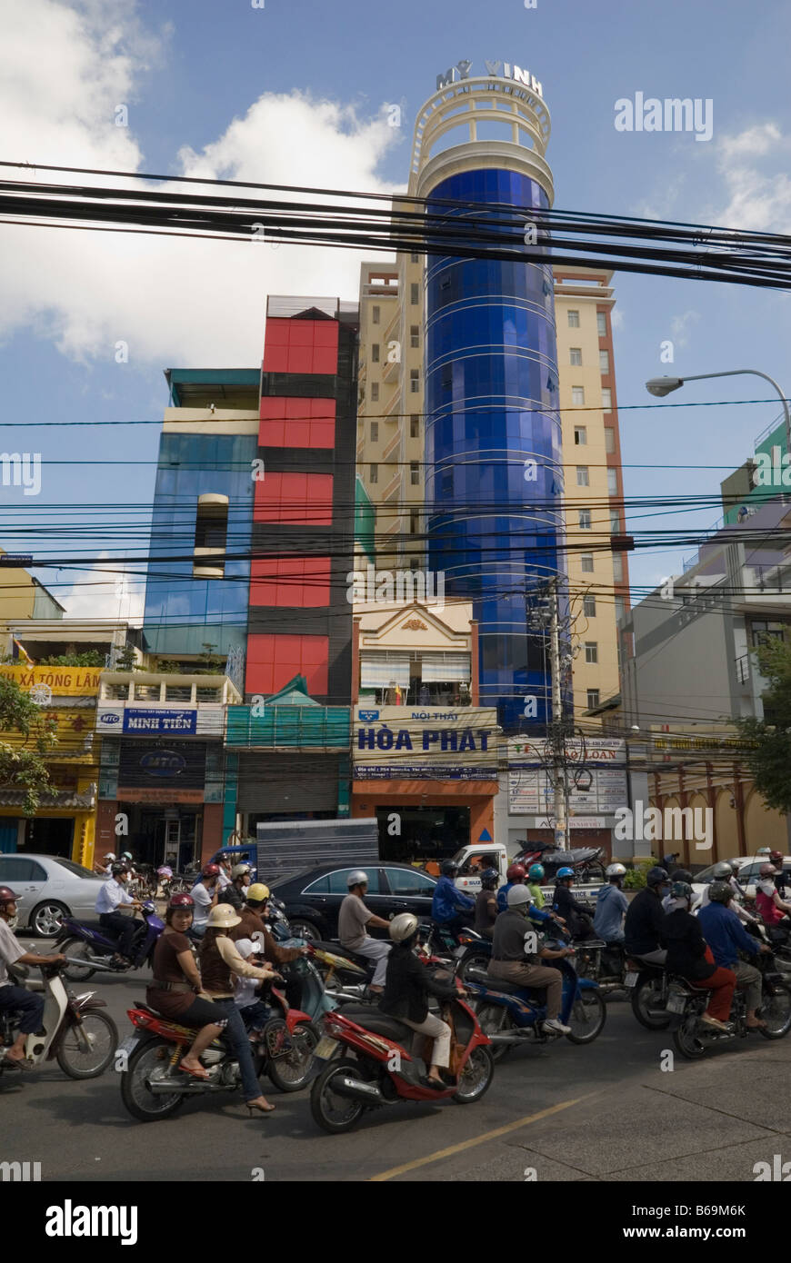 Linee elettriche al di sopra di un caotico traffico intasato Street di fronte ad un edificio moderno nella città di Ho Chi Minh, Vietnam Foto Stock