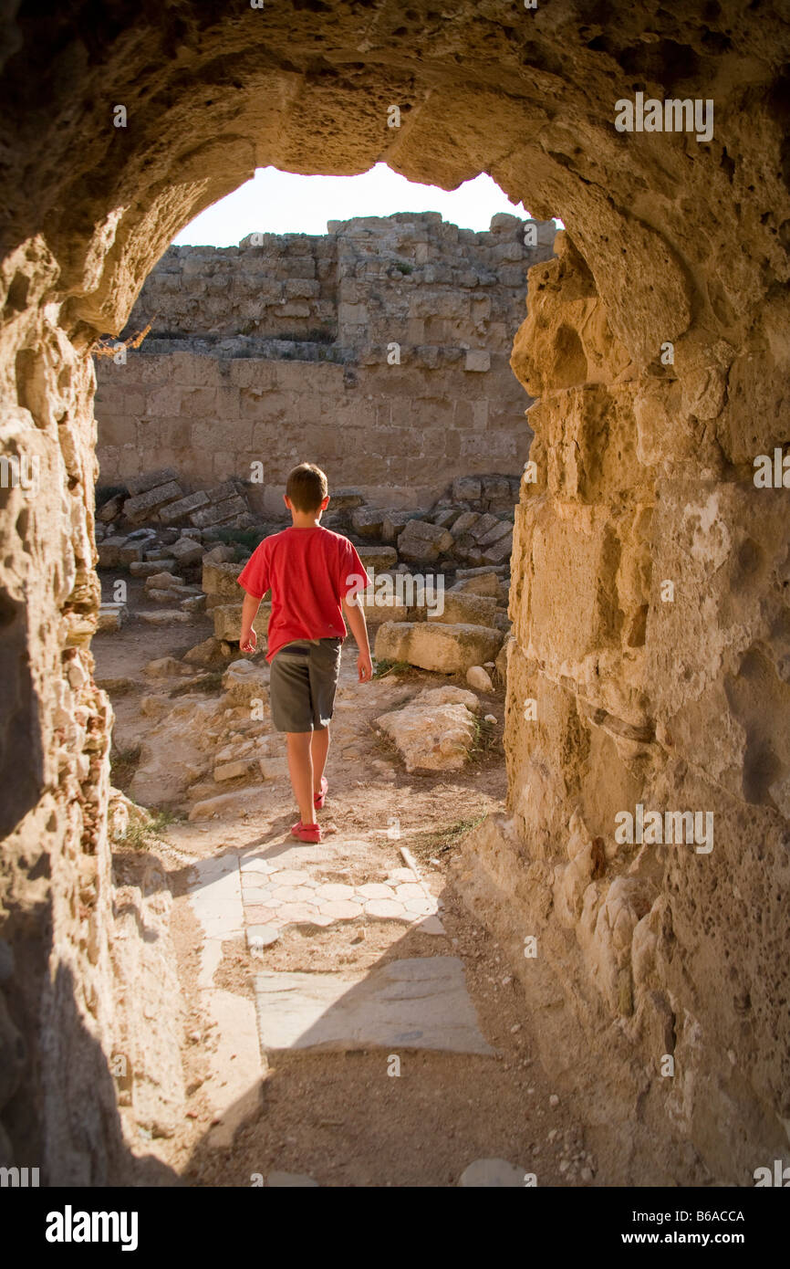 Ragazzo a piedi attraverso un arco a Salamina sito archeologico romano la parte settentrionale di Cipro Foto Stock