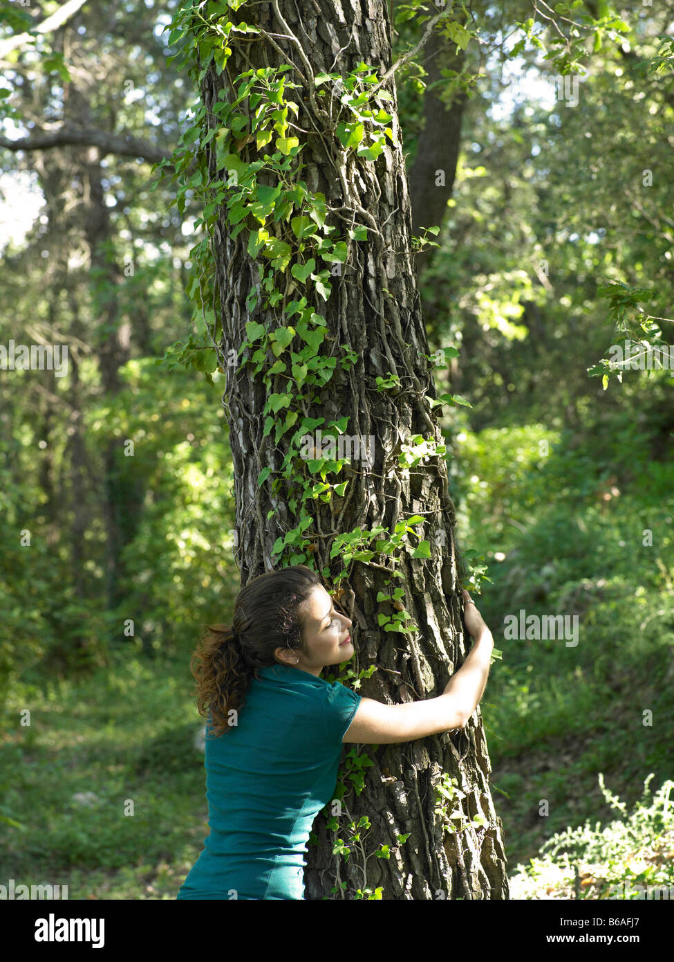 Giovane donna abbracciando tree Foto Stock