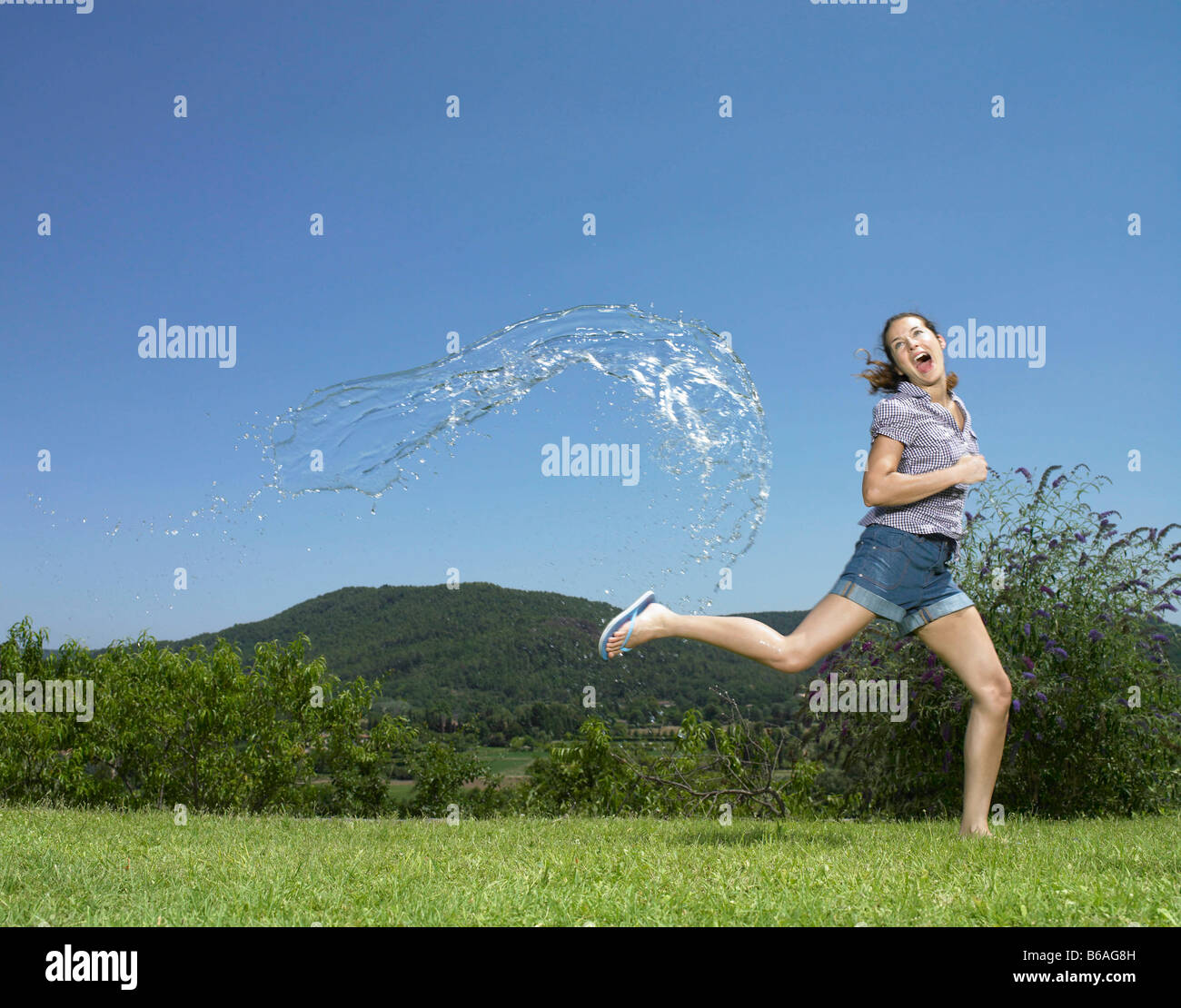 Ragazza che corre da arc di acqua Foto Stock