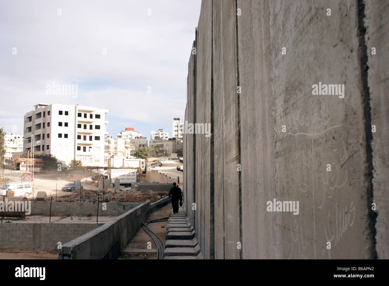 Un uomo palestinese da passeggiate incompiuto, il muro di separazione nei territori occupati della Cisgiordania città di Al-Ram, Palestina Foto Stock