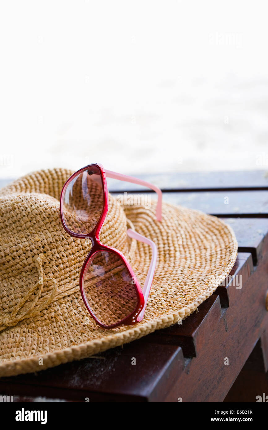 Cappello di paglia e occhiali da sole sulla sedia a sdraio Foto Stock