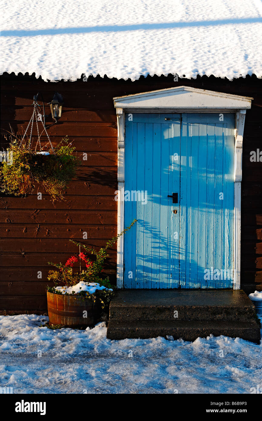 Porta blu sulla costruzione in legno con coperta di neve tetto Foto Stock