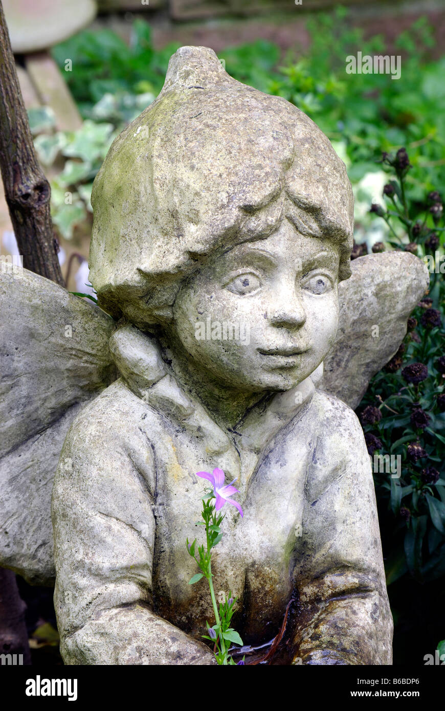 Angelo scultura statua con cheeky faccia e sola campana-fiore Foto Stock