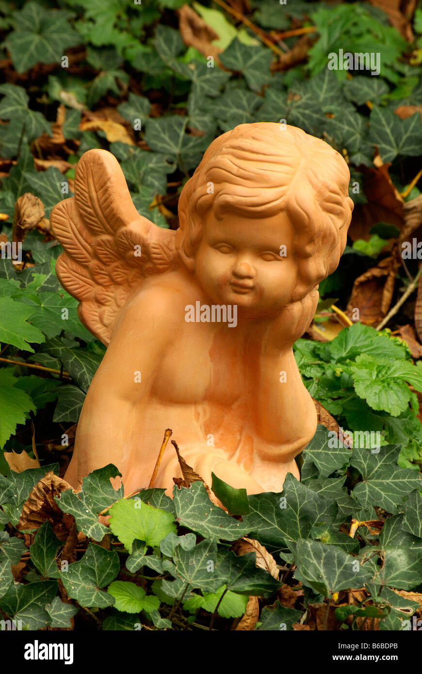 Angelo statua scultura ceramica marrone nel mezzo di edera Foto Stock