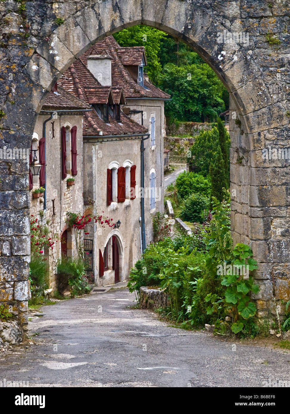Visualizzazione attraverso l'arcata in pietra di una via del borgo rurale in Francia Foto Stock