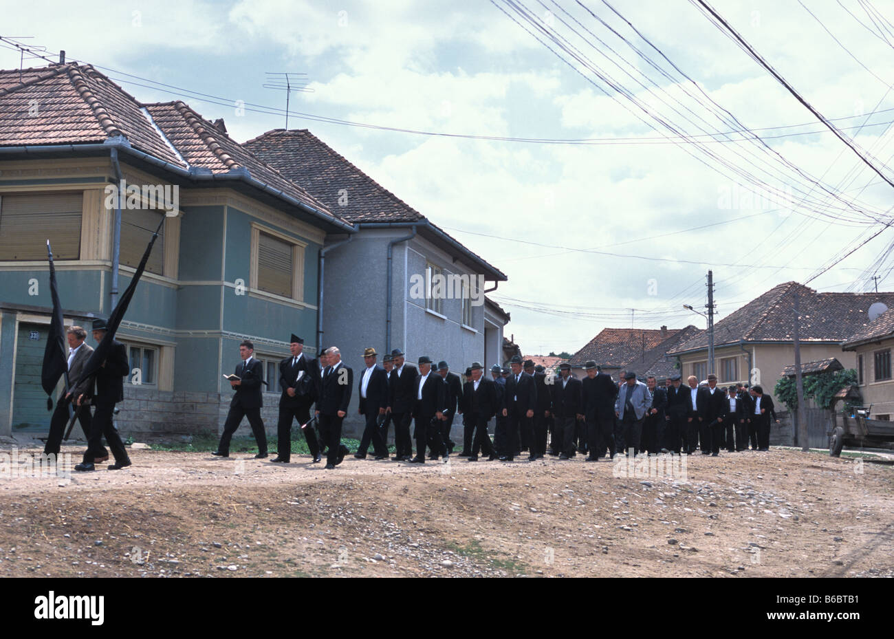 Gli uomini camminare al funerale di seppellire Gizella Kocisis invecchiato 89 in Szekelyderz o villaggio Dariju transilvania ROMANIA Foto Stock