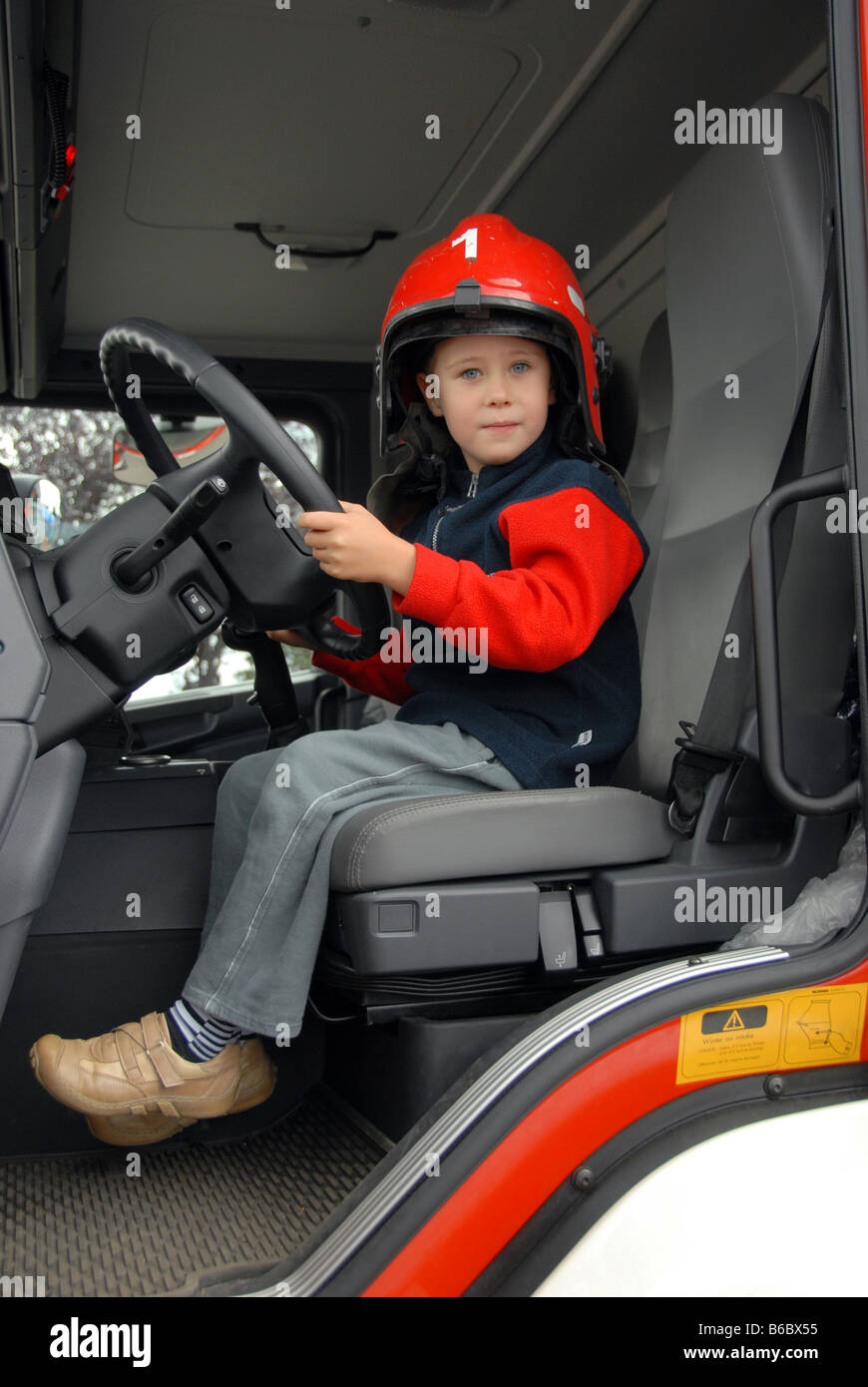 Un giovane ragazzo seduto in un camion dei pompieri Foto Stock