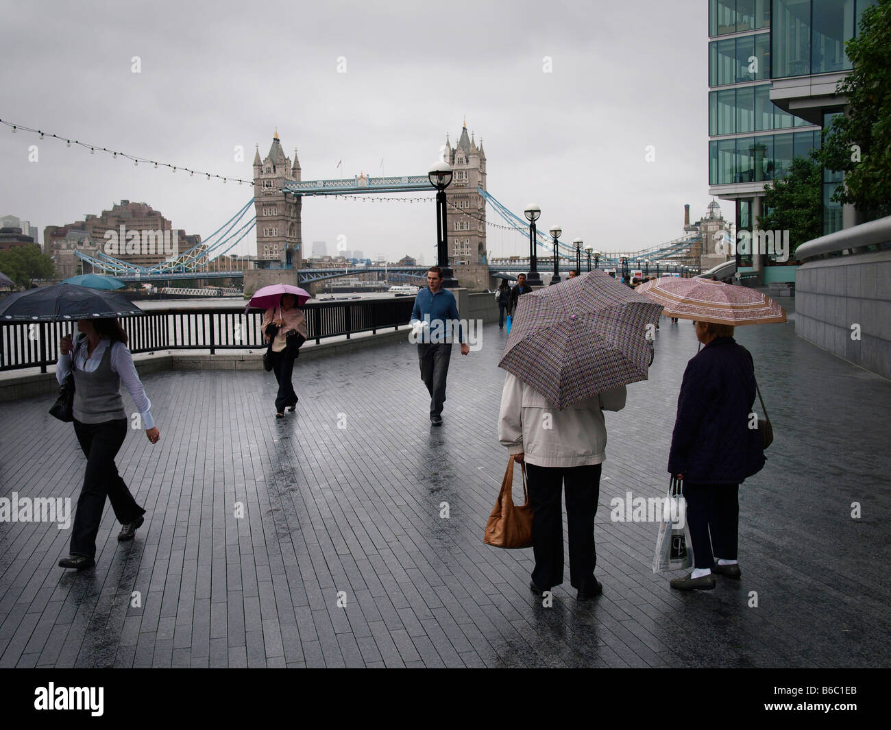 Le persone che visitano Londra sotto la pioggia il Tower Bridge turisti ombrelloni Foto Stock
