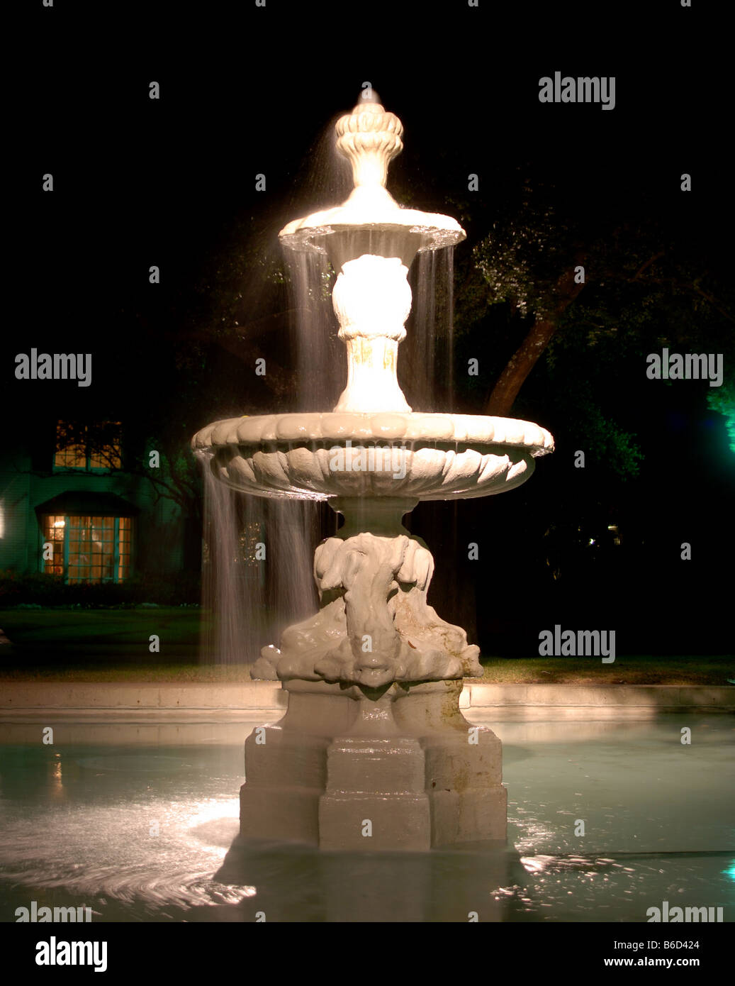 Bianco fontana di acqua nella piscina illuminata di notte Foto Stock