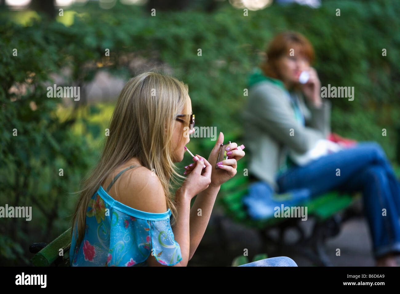 La Russia, San Pietroburgo, giardino estivo ( Letnij sad ). Giovane donna mettendo il rossetto sulle labbra. Foto Stock