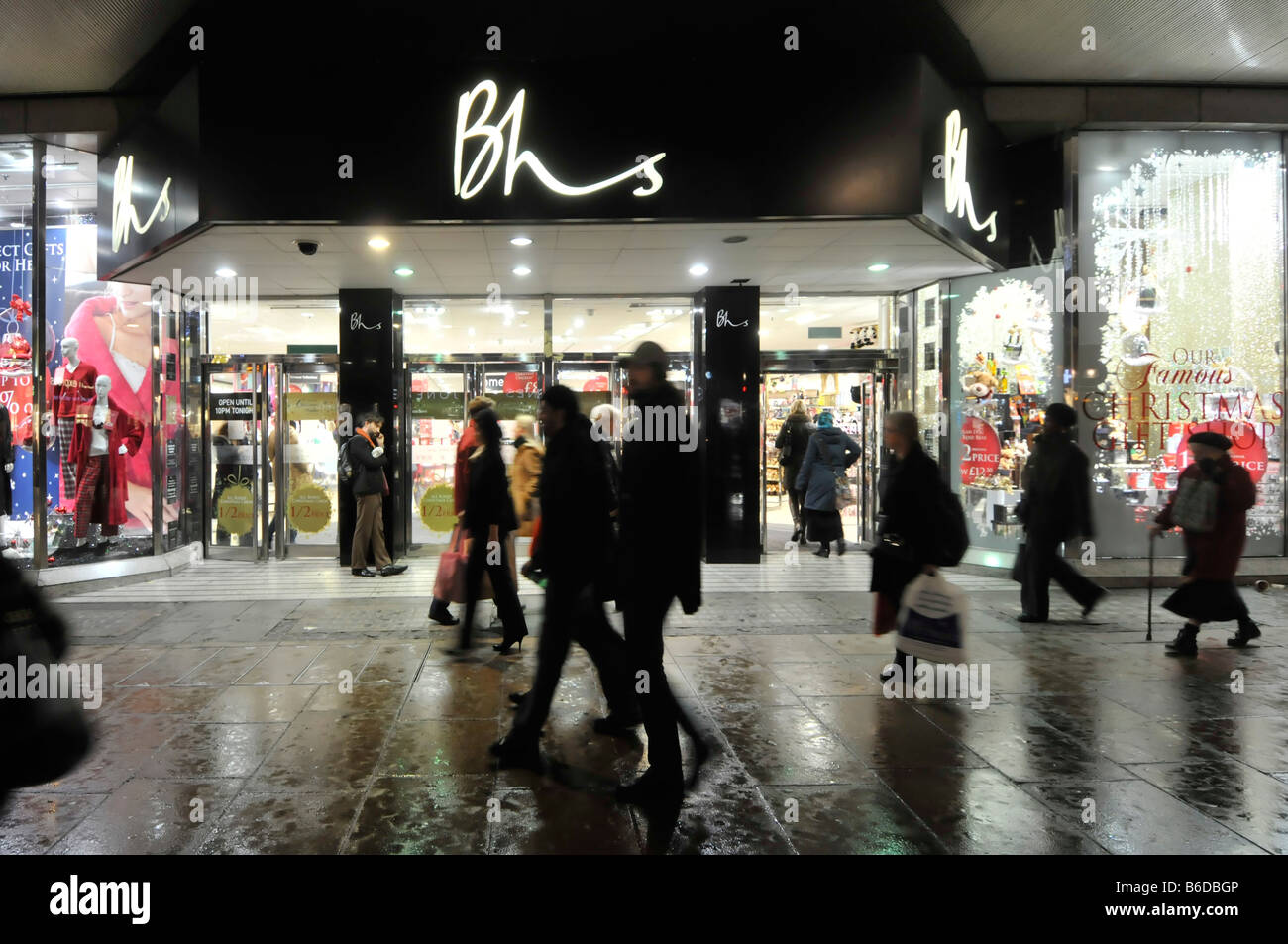 London Oxford Street silhouette acquirenti camminare su bagnato marciapiede West End BHS British Home Stores negozio di affari negozio al dettaglio davanti al cartello UK shopping Street Foto Stock