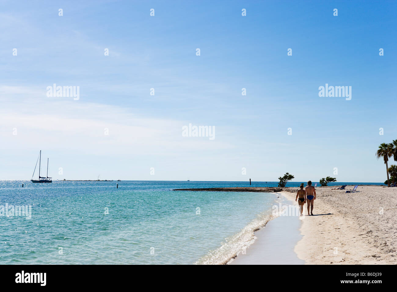 Paio di camminare sulla spiaggia con uno yacht in distanza, Sombrero Beach, Vaca Key, maratona, Florida Keys Foto Stock